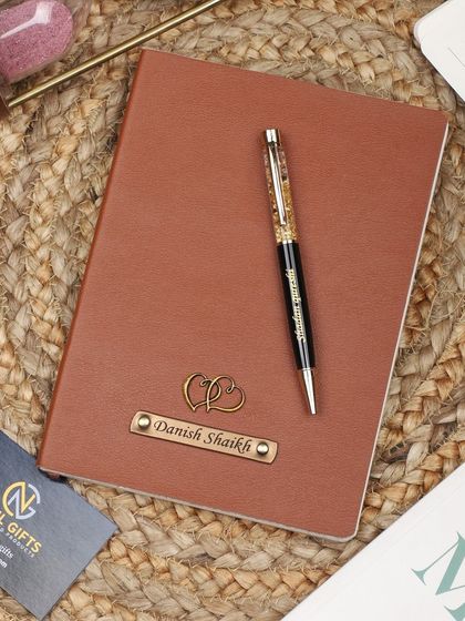 A personalized leather diary and pen set, perfect for gifting. This one is customized with a name and a double heart charm.