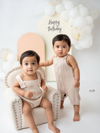 A first birthday portrait for twins in a simple, modern studio setting.