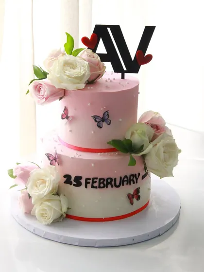 A two-tiered wedding cake in ombre pink colored ganache, decorated with fresh flowers and delicate wafer paper butterflies. The flavor inside was a delicious butterscotch.