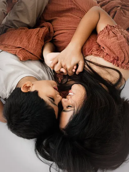 An artistic overhead shot of a mother and son holding hands. The warm tones and intimate pose create a portrait that is both beautiful and deeply emotional.