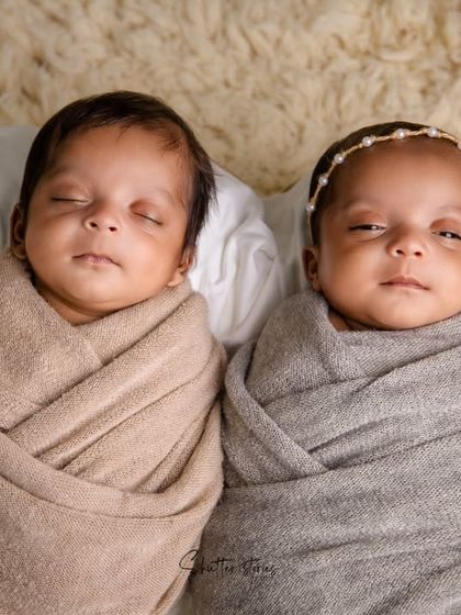 A sweet portrait of twin babies side-by-side, wrapped in complementary neutral tones of beige and grey.