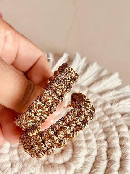 Holding the golden hoops to show their size and texture. They are comfortable to wear all day.