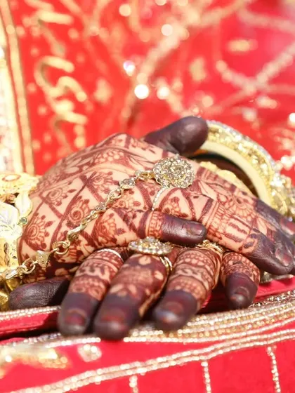 The bride's hands, adorned with a dark henna stain and beautiful jewelry. A deep stain is an essential part of the complete bridal look.