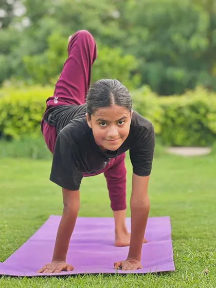 A young yogini works on a twisting balance pose on the mat outdoors. Poses like this are great for improving coordination and focus in a fun way.