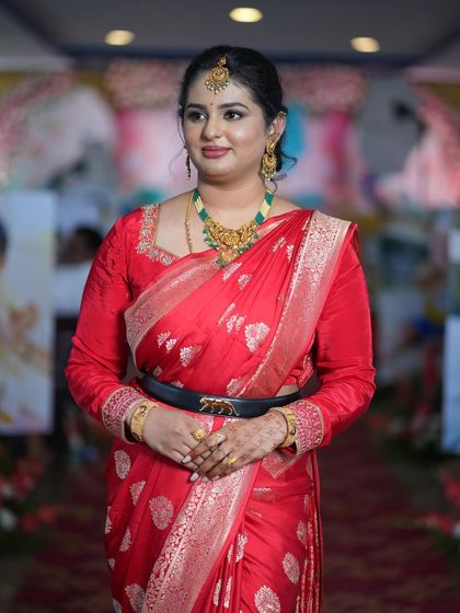 Prathibha looking regal in a vibrant red saree for the naming ceremony. The look is tied together with a modern belt for a contemporary twist on traditional wear.