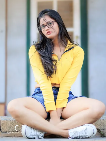 A cool and casual seated pose. The addition of glasses adds a touch of intellectual chic to the look.