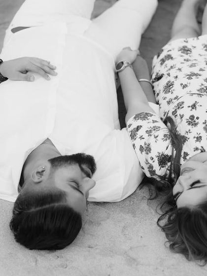 An intimate black and white photo of the couple lying on the sand, creating a timeless and romantic pre-wedding portrait.