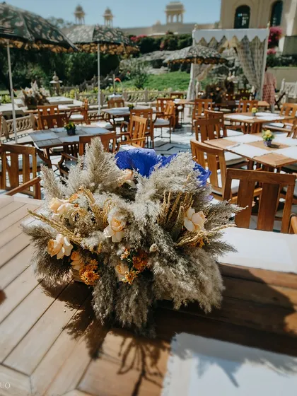 A beautiful pampas grass and dried flower centerpiece on a wooden dining table. This arrangement adds a touch of soft, earthy elegance to the outdoor luncheon.