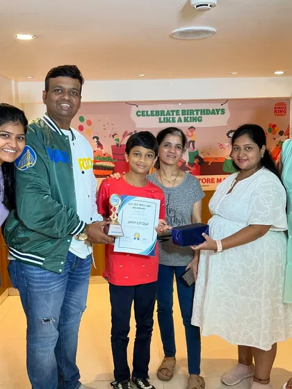Darsh proudly receives his award for completing the 1st level of Abacus, surrounded by his supportive family.
