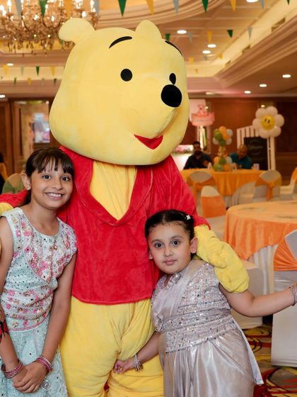 A Winnie the Pooh mascot giving hugs and posing for photos with young guests. Costumed characters are a fantastic way to bring a theme to life.