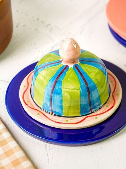 The butter dish styled with a dark blue plate, creating a bold color contrast. This shows the versatility of the piece with different color schemes.