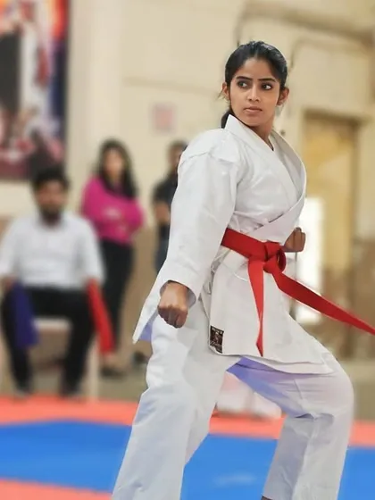 A dynamic pose captured mid-kata. The student's body is coiled with potential energy, ready to unleash a powerful block or strike.