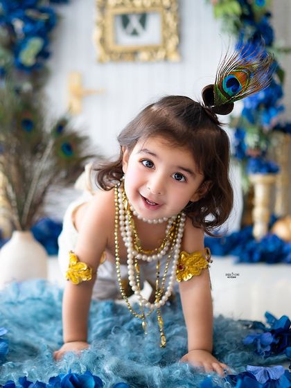 A playful crawling pose from this little girl dressed as Krishna, with a peacock feather in her hair.