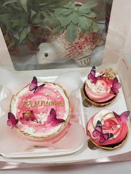 Another view of the pink butterfly bento box, showcasing the delicate details on the mini cake and cupcakes. All my creations are 100% eggless and made with care.