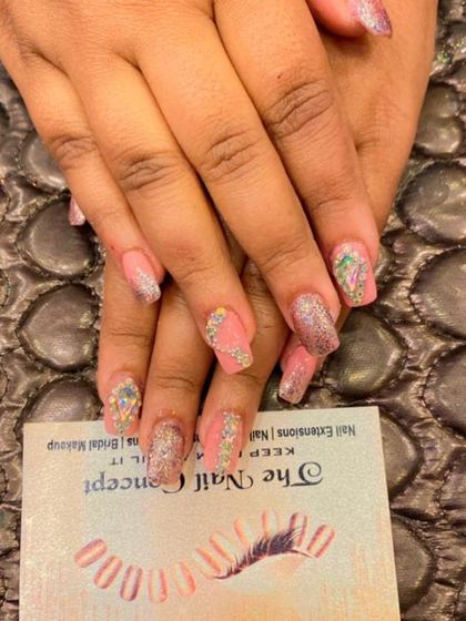 A soft and sparkly design on pink nails. The look is enhanced with glitter and intricate, multi-colored crystal work for a dazzling finish.