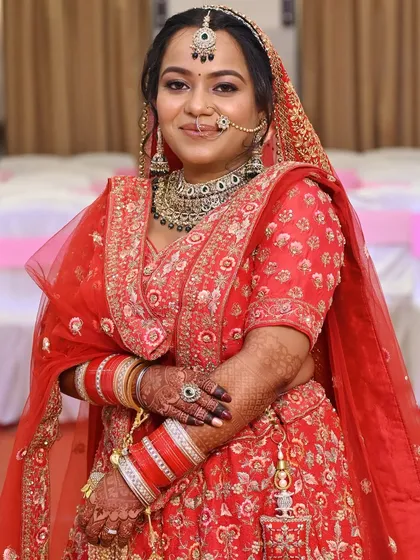 A full-length portrait of the bride in her traditional red Punjabi wedding outfit.