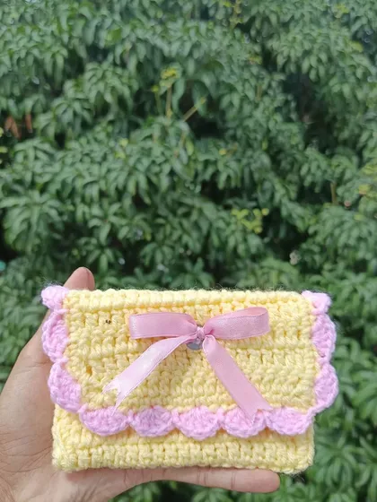 A close-up of the yellow and pink pocket purse. The satin ribbon adds a delicate finishing touch.
