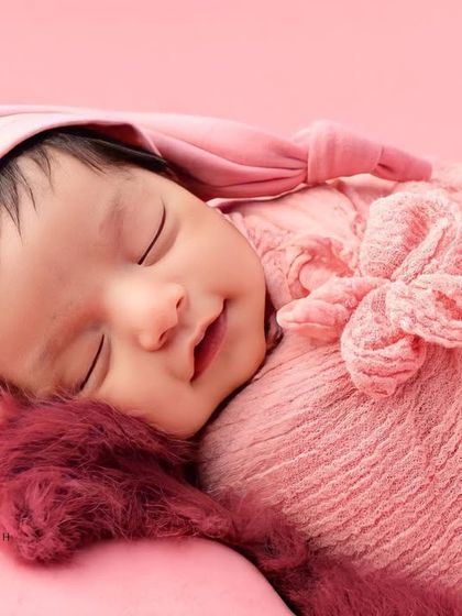 A heart-melting smile from a sleeping baby in a pink hat and wrap. These are the moments we live for.