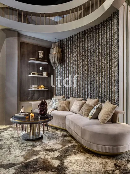 A refined blend of luxury and comfort. This interior features a plush curved sofa set against a textured feature wall that adds depth and dimension. Rich materials, layered lighting, and sculptural decor create a sophisticated yet inviting ambiance.
