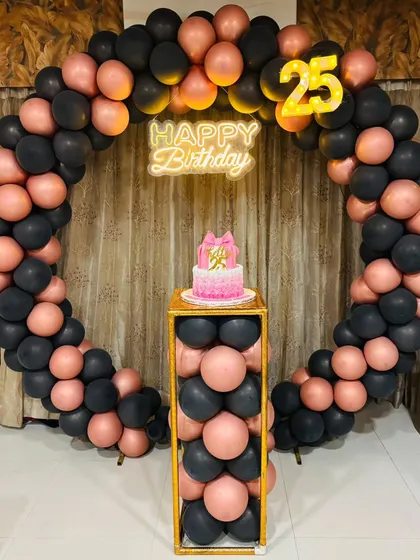 A stylish pink ombre cake for a 25th birthday, set against a modern balloon arch. The cake itself is the centerpiece of this chic celebration.
