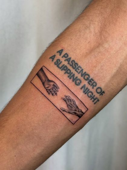 A memorial tattoo that tells a story of love and loss. It features the iconic "Creation of Adam" hands, symbolizing a connection that transcends the physical, with the poignant phrase "A passenger of a slipping night."