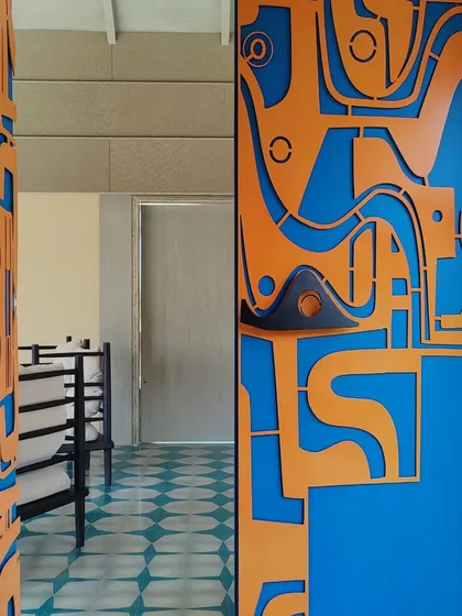 A door is never just a door for us. This custom-fabricated metal door, with its bold orange and blue abstract design, acts as a powerful architectural statement, setting the tone for the entire home before you even step inside.