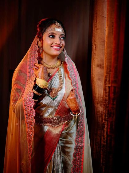 A candid bridal portrait, capturing the bride's natural smile and the beautiful details of her veil and saree under soft, flattering light.