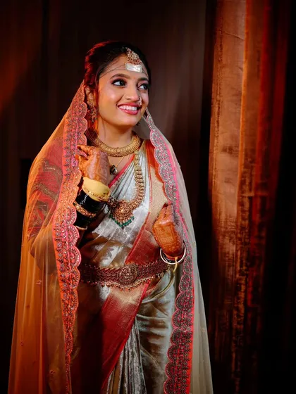 A candid bridal portrait, capturing the bride's natural smile and the beautiful details of her veil and saree under soft, flattering light.