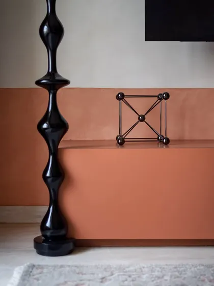 A close-up of the TV unit, showing the sculptural black turning and the simple, modern console.