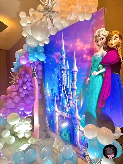 Life-sized cutouts of Queen Elsa and Princess Anna stand beside the glowing castle backdrop, making for a perfect photo opportunity for all the little guests.