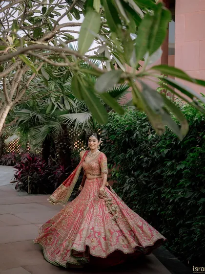 A full-length shot showcasing the magnificent bridal lehenga in all its glory. The bride looks like royalty as she takes a stroll through the beautiful venue gardens.