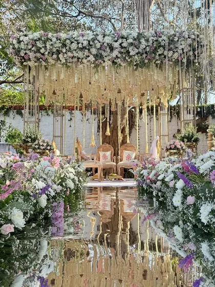 A modern fairy tale comes to life. This mandap combines a reflective mirror aisle with a cascade of lilac and white florals, creating a breathtaking space for you to say your vows.