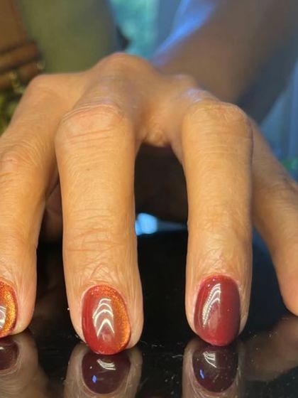 A warm, reddish-brown cat-eye effect on short, rounded nails for a subtle, earthy look.