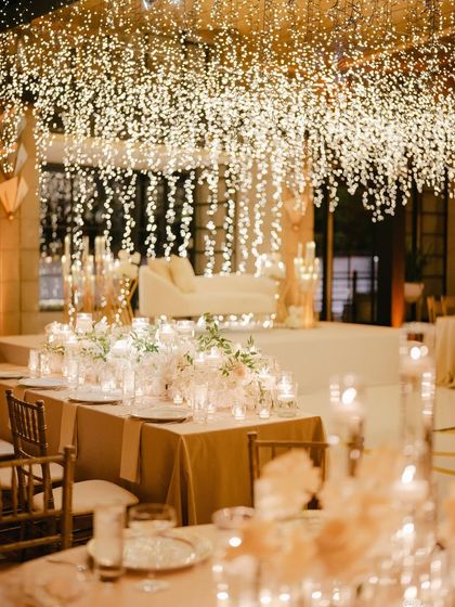 A beautiful shot of the reception decor. The tables are set under a ceiling of cascading fairy lights, creating a magical and romantic ambiance for the evening.