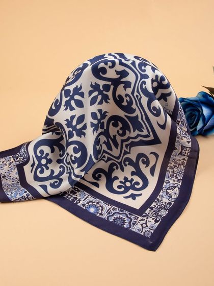 The tile-patterned pocket square folded and styled with a blue rose, highlighting its design.