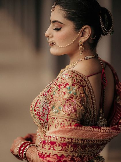 A classic profile shot highlighting the bride's elegance. This portrait focuses on her intricate jewelry, her traditional nath, and the graceful line of her posture.