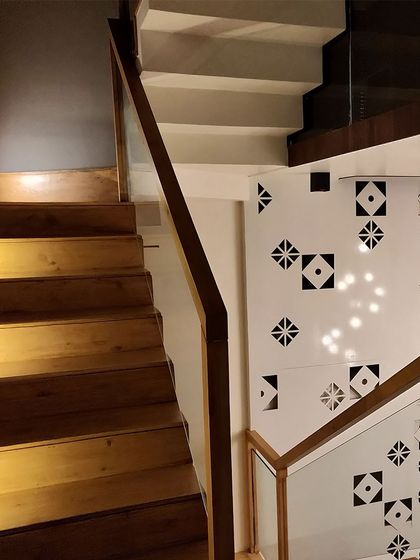 The contrast between the dark, smooth wood of the stairs and the bright, patterned wall creates a dynamic visual effect.