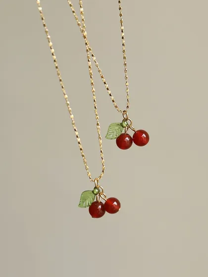 A detailed shot of the cherry charm necklaces. These are made with high-quality materials to ensure they last and bring a smile to your face.