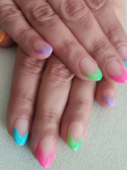 A playful and modern take on the French manicure, with vibrant, multicolored tips in shades of pink, green, blue, and purple.