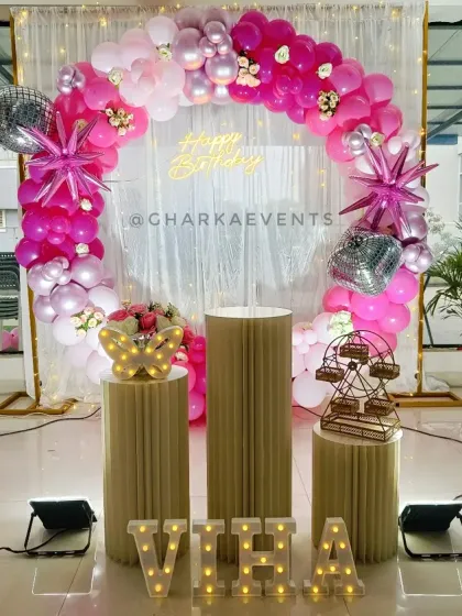 A glamorous pink and silver setup for Viha's 6th birthday, featuring a shimmer curtain and starburst foil balloons.