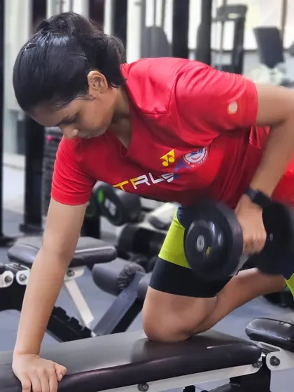 A player performs a dumbbell row, an essential exercise for building back strength which is crucial for powerful smashes and overall stability.