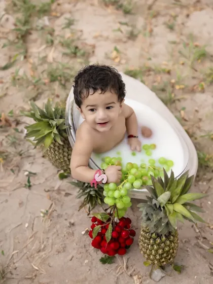 A unique and playful milk bath session is a perfect way to celebrate a milestone. This outdoor setup with fresh fruits creates a beautiful, natural setting for capturing your baby's delightful curiosity.