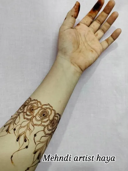 A simple and elegant rose band on the forearm. This minimalist design is perfect for someone who wants a touch of henna without a full-hand design.