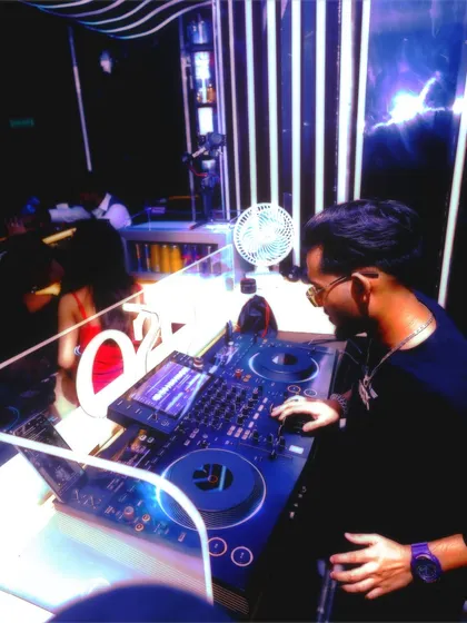 Side view from the DJ booth, showing my setup and the club's modern interior. I am experienced in working with various professional sound and lighting systems.