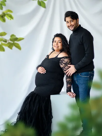 A cozy and classic studio portrait. The simple black outfits and white background keep the focus on the couple's connection.