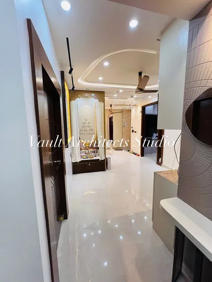 A view down the hallway of a newly completed apartment. This image captures the cohesive design language, from the polished floors and elegant pooja mandir to the textured wall panels in the living area.