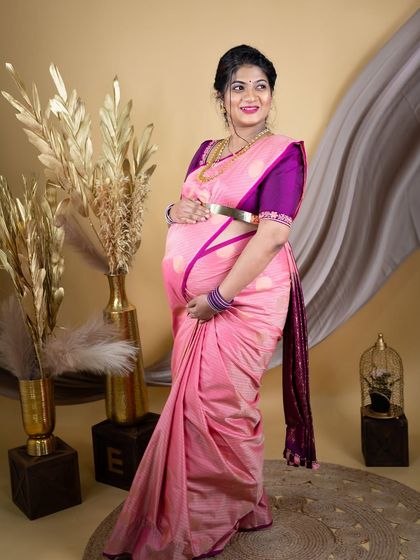 A solo portrait of a mom-to-be in a lovely pink silk saree. The shot is taken in our studio against a neutral backdrop, letting the beauty of the saree and her expression shine.