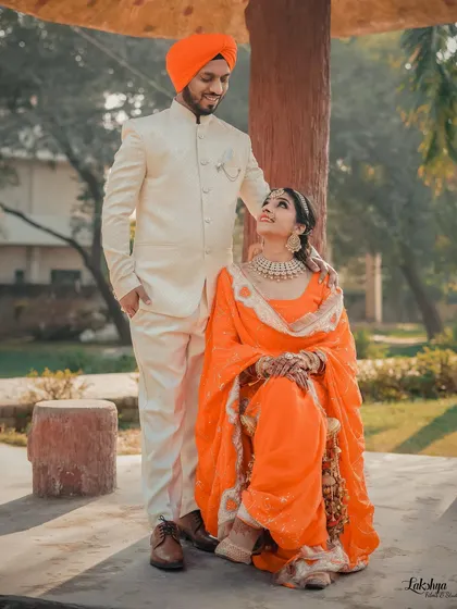 A beautifully composed portrait from a pre-wedding session. The groom stands protectively over his seated bride, both sharing a look of love and admiration.