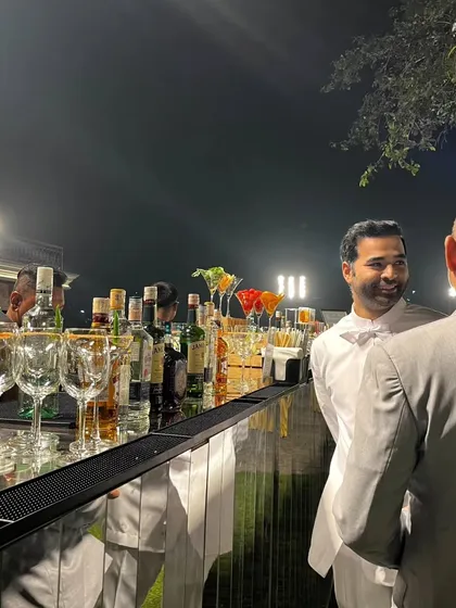 A candid moment at our sleek, mirrored bar during an outdoor evening event. The reflection of the open night sky and the warm interactions between guests showcase the inviting atmosphere we help create.