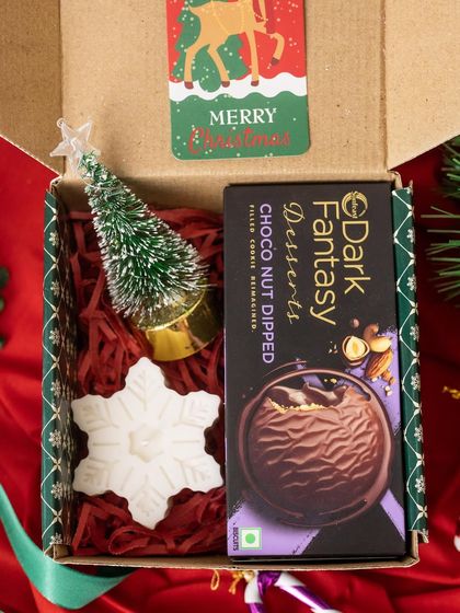 This budget-friendly Christmas box is packed with festive charm. It includes a mini Christmas tree, a snowflake candle, and a box of Dark Fantasy chocolates.